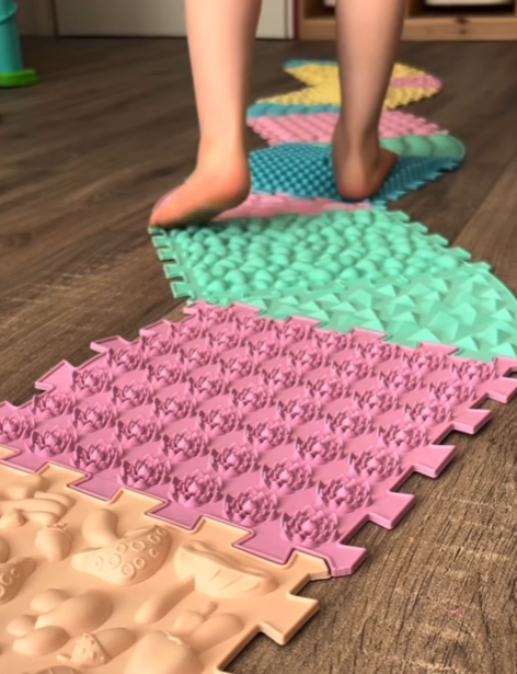 Detail barevných puzzle podložek Ortek s dětskýma nohama